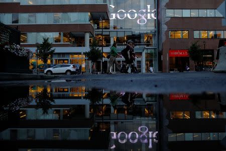 The Google sign is reflected in a rain puddle outside their offices in Cambridge, Massachusetts, U.S., June 27, 2017. REUTERS/Brian Snyder