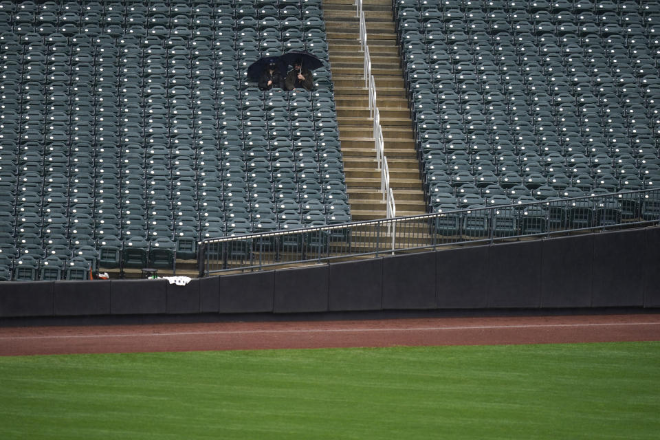 Fans sit in the rain before a baseball game between the New York Mets and the Philadelphia Phillies at Citi Field, Thursday, April 15, 2021, in New York. The game was postponed due to rain. (AP Photo/Seth Wenig)