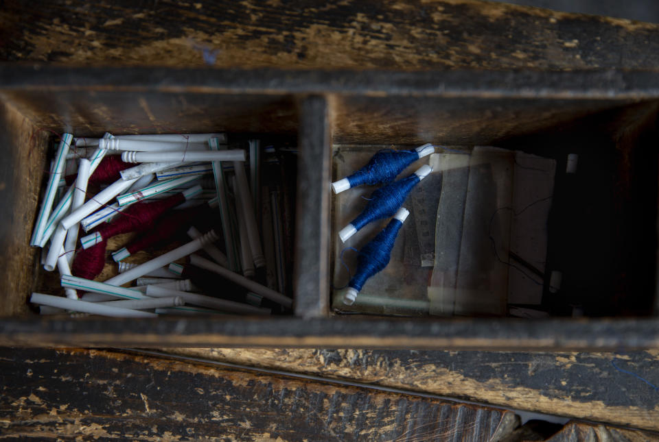 Pashmina threads spun on plastic straws lie inside a wooden box near a loom in Srinagar, Indian controlled Kashmir, Saturday, June 13, 2020. A months-long military standoff between India and China has taken a dire toll on local communities as tens of thousands of Himalayan goat kids die because they couldn't reach traditional winter grazing lands, officials and residents said. Nomads have roamed these lands atop the roof of the world for centuries, herding the famed and hardy goats that produce the ultra-soft wool known as Pashmina, the finest of cashmeres. Cashmere takes its name from the disputed Kashmir valley, where artisans weave the wool into fine yarn and exquisite shawls that cost up to $1,000 apiece in world fashion capitals in a major handicraft export industry that employs thousands. (AP Photo/Dar Yasin)