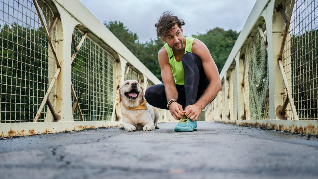  Man kneeling on bridge with dog. 