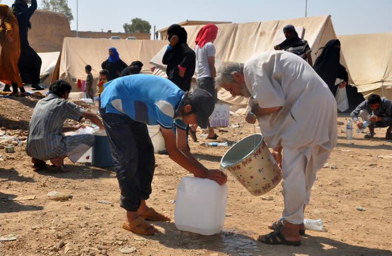 Displaced Syrians fill a container with water at a makeshift camp in Hasakeh province on August 13, 2017