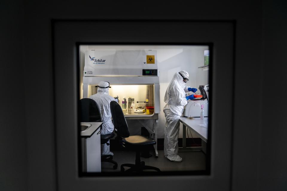 In this photo taken on Wednesday, April 29, 2020, medical workers wearing special suits to protect against coronavirus, work with samples for a PCR test for the COVID-19 coronavirus at a hospital in Ternopil, Ukraine. Ukraine's troubled health care system has been overwhelmed by COVID-19, even though it has reported a relatively low number of cases. (AP Photo/Evgeniy Maloletka)