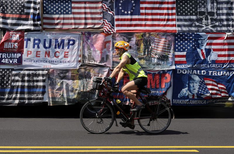 A bicyclist passes by the truck of a Trump campaign memorabilia vendor as protestors rally against the coronavirus disease (COVID-19) restrictions during a rally held outside the Pennsylvania State Capitol Building in Harrisburg, Pennsylvania