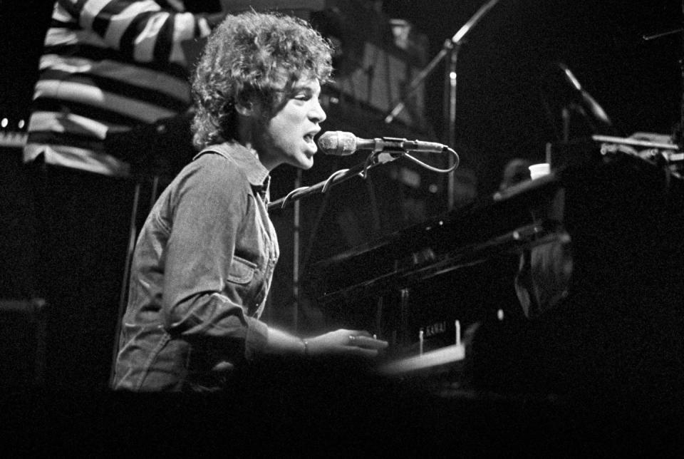 eric carmen sitting at a piano and singing into a microphone