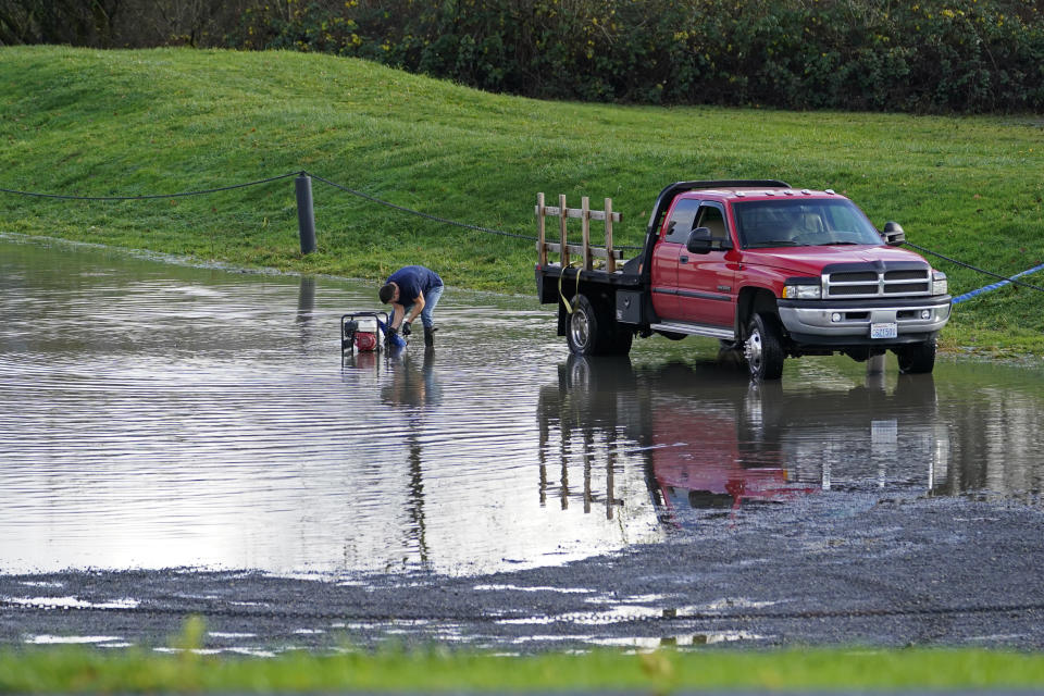 A person works to pump water to the other side of a levee after flooding near Everson, Wash., Monday, Nov. 29, 2021. Localized flooding was expected Monday in Washington state from another in a series of rainstorms, but conditions do not appear to be as severe as when extreme weather hit the region earlier in November. (AP Photo/Elaine Thompson)