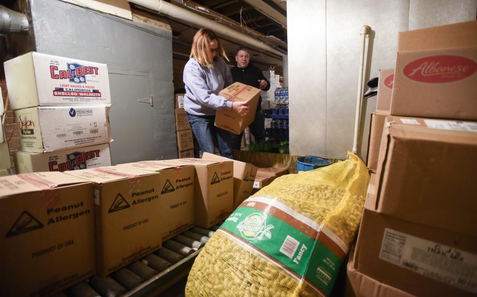 Tammy Melsner, former owner of the Peanut Shop in downtown Lansing, shows new co-owner Adam Seyburn the ropes of rotating stock and general operations of the store, Monday, Dec. 6, 2021.