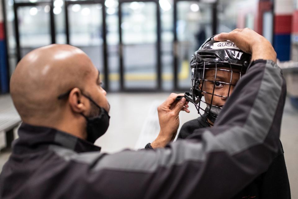 Leon Sims helps puts a helmet on his son Quenton Sims, 7, before hockey practice at the Jack Adams Memorial Arena in Detroit on Wednesday, May 4, 2022.