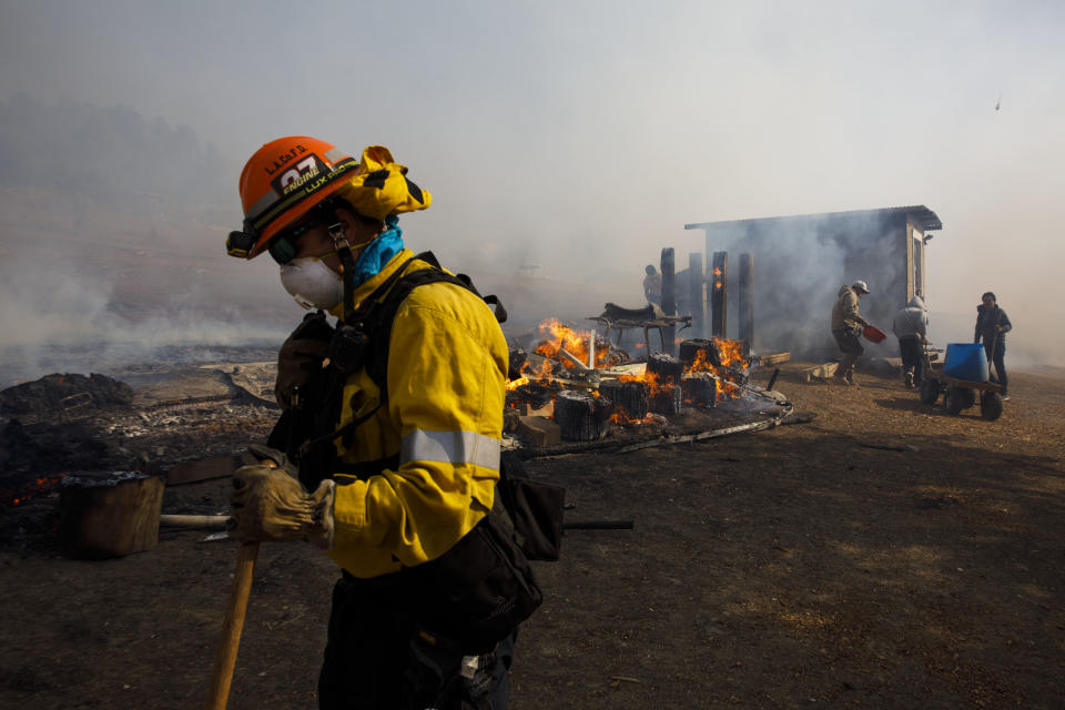 Firefighters and workers try to extinguish smoldering embers on a ranch during the Easy Fire in Simi Valley, Calif. on Oct. 30, 2019. (Photo: Patrick T. Fallon/Bloomberg via Getty Images)