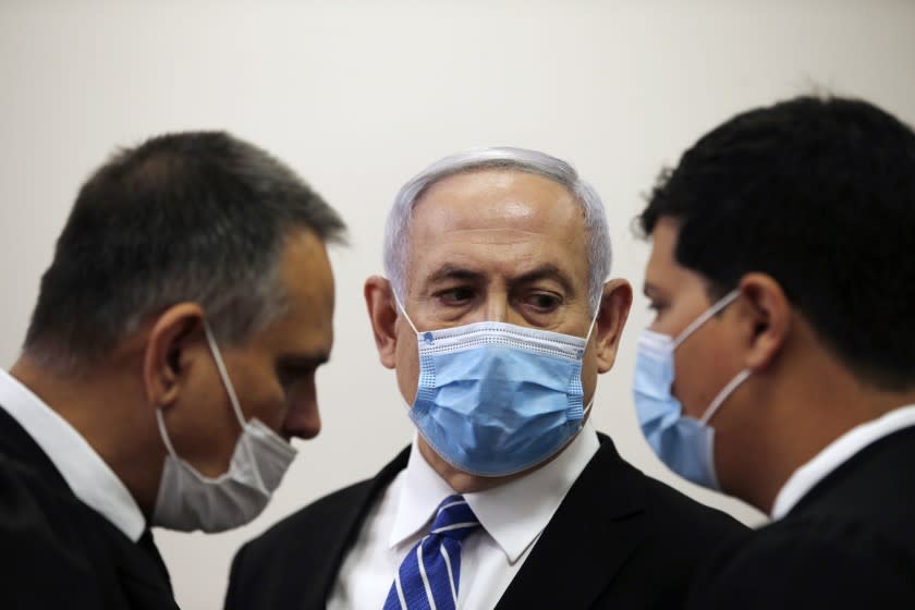 Israeli Prime Minister Benjamin Netanyahu, wearing a face mask in line with public health restrictions due to the coronavirus pandemic, looks at his lawyer inside the court room as his corruption trial opens at the Jerusalem District Court, Sunday, May 24, 2020. He is the country's first sitting prime minister ever to go on trial, facing charges of fraud, breach of trust, and accepting bribes in a series of corruption cases stemming from ties to wealthy friends. (Ronen Zvulun/ Pool Photo via AP)