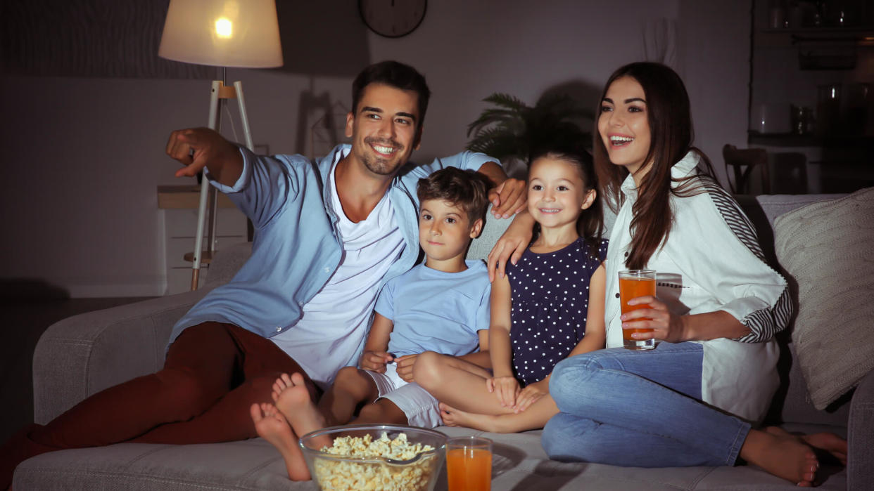 Happy family watching TV on sofa at night