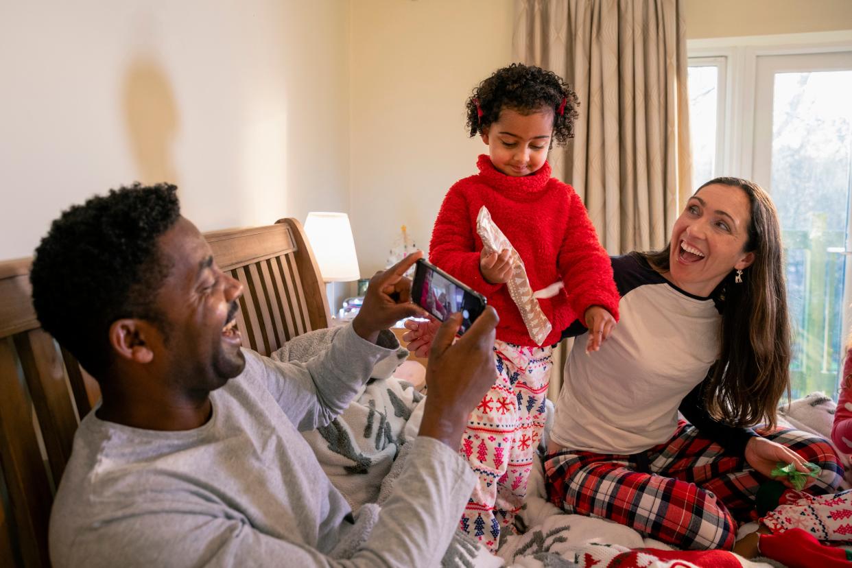 A father filming his little girl as she opens up one of her Christmas presents (Getty Images)