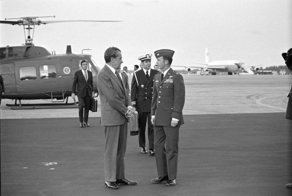 In this photo obtained by the National Security Archive from the Richard M. Nixon Presidential Library, Nixon speaks with senior Air Force officers, with Presidential Emergency Satchel carrier Lt. Commander T. Stephen Todd in the immediate background, at Homestead Air Force Base, Fla., on March 11, 1974. (Richard M. Nixon Presidential Library/National Security Archive - nsarchive.gwu.edu via AP)