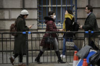 A woman wearing a face mask walks through the City of London in London, Wednesday, March 4, 2020. British authorities laid out plans Tuesday to confront a COVID-19 epidemic, saying that the new coronavirus could spread within weeks from a few dozen confirmed cases to millions of infections, with thousands of people in the U.K. at risk of death. (AP Photo/Matt Dunham)