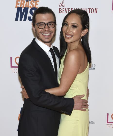 A man in a suit embracing a woman in a pastel yellow gown