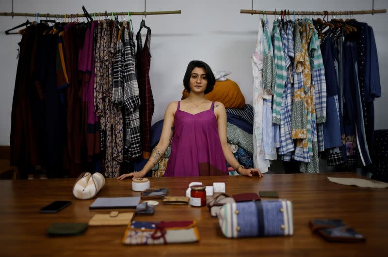 Kriti Tula, a fashion designer, poses for a picture as she stands next to the clothes made from discarded fabric waste, at her factory in New Delhi