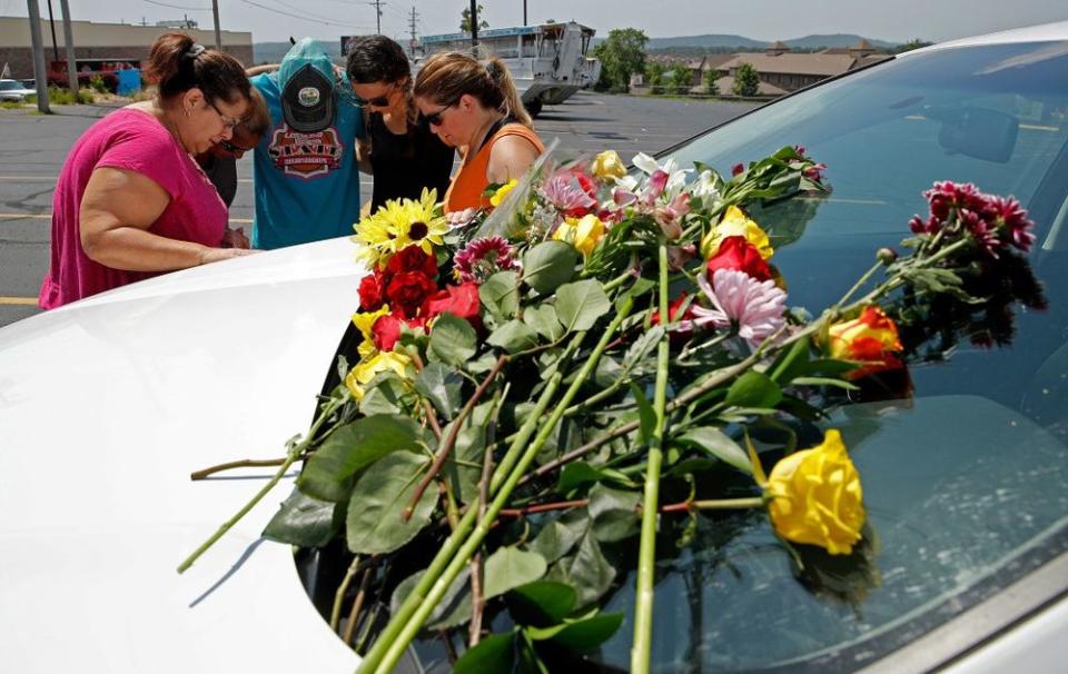 People pray next to a car believed to belong to a victim of a last night's duck boat accident, in Branson, Missouri