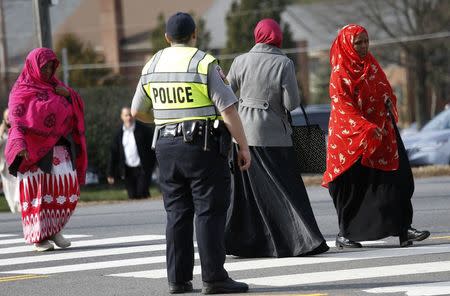 A Fairfax County police officer controls traffic as women make their way to the Dar Al-Hijrah Islamic Center in Falls Church, Virginia just outside of Washington December 11, 2015. REUTERS/Kevin Lamarque
