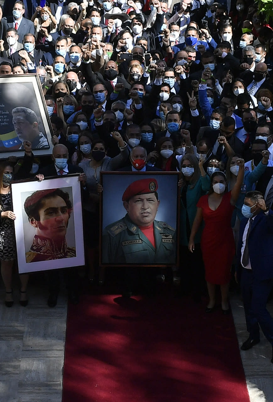 Incoming parliamentary members carry images of late Venezuelan President Hugo Chavez, center, and independence hero Simon Bolivar, to move them from the chamber of the Constitutional Assembly to the chamber of the National Assembly, as the ruling socialist party prepares to assume the leadership of Congress in Caracas, Venezuela, Tuesday, Jan. 5, 2021. Ruling party allies swept legislative elections last month boycotted by the opposition. Holding the portraits are, from right, First Lady Cilia Flores, Diosdado Cabello, president of the Constitutional Assembly, Jorge Rodriguez, the newly elected National Assembly president, and Iris Varela, first vice president of Congress. (AP Photo/Matias Delacroix)