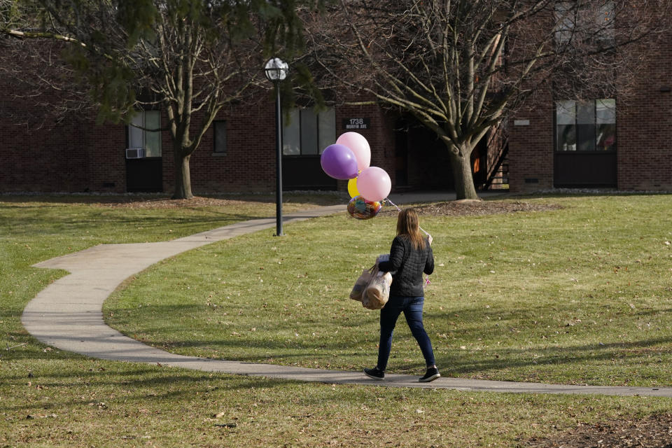 Erica Stowe delivers groceries and balloons to a student, Thursday, Nov. 19, 2020, in Ann Arbor, Mich. A group of parents has come together to help support University of Michigan students while they are sick or quarantining. The group of mostly moms was started and is organized by Sherry Levine of Rye Brook, New York, who's also a mother of a Michigan student. After she spread the word on parent pages on Facebook, local volunteers stepped up to help fulfill student requests by dropping off groceries or supplies. (AP Photo/Carlos Osorio)