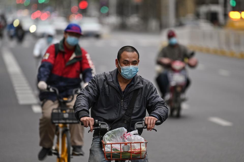 People wearing face masks ride bicycles on a street in Wuhan, in China's central Hubei province, on April 1, 2020, where the COVID-19 coronavirus first emerged last year but is partly reopening after more than two months of near total isolation. (Photo by Hector RETAMAL / AFP) (Photo by HECTOR RETAMAL/AFP via Getty Images)