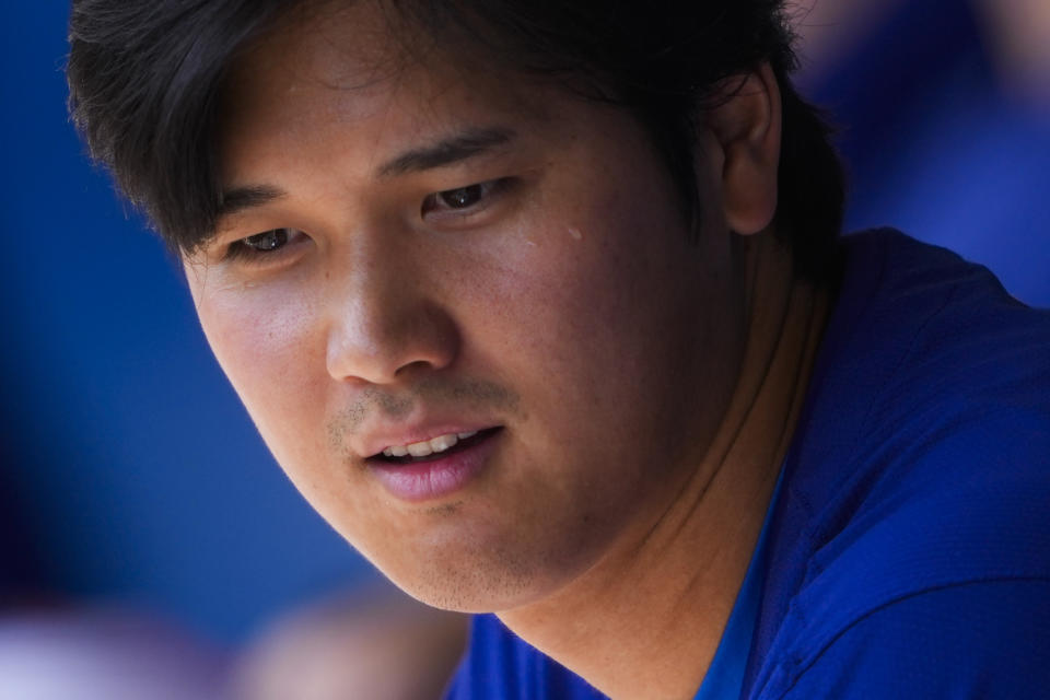 Los Angeles Dodgers designated hitter Shohei Ohtani sits in the dugout during a spring training baseball game against the Arizona Diamondbacks, Sunday, March 10, 2024, in Phoenix. (AP Photo/Lindsey Wasson)