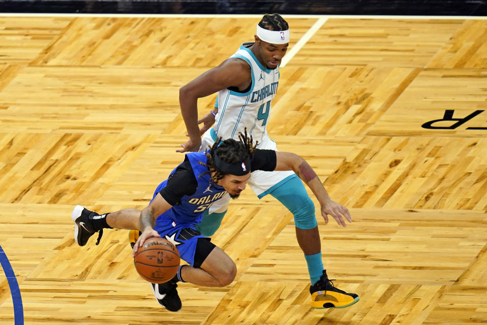 Orlando Magic guard Cole Anthony, left, is tripped up by Charlotte Hornets guard Devonte' Graham (4) as he drives downcourt during the second half of an NBA basketball game, Sunday, Jan. 24, 2021, in Orlando, Fla. (AP Photo/John Raoux)