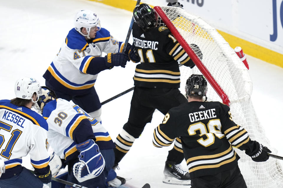 Boston Bruins center Trent Frederic (11) is checked by St. Louis Blues defenseman Torey Krug (47) during the first period of an NHL hockey game, Monday, March 11, 2024, in Boston. (AP Photo/Charles Krupa)