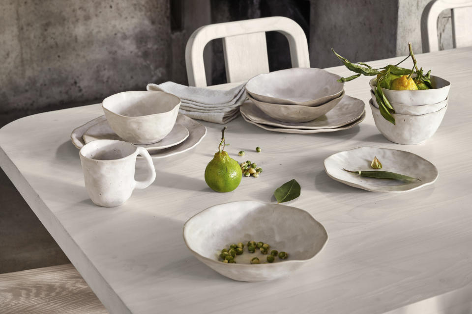 This image provided by Crate & Barrel shows dining plates, bowls and cups. Crate and Barrel, designer Leanne Ford's Kiln wonky dinnerware looks fresh off the potter's wheel. Many chefs are using creative dishware designed with irregular shapes and unusual colors to help create a mood. (Crate & Barrel via AP).
