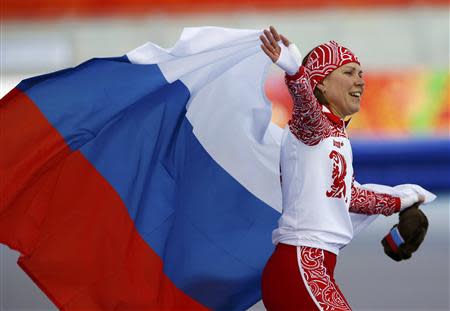 Russia's Olga Graf holds up her national flag and celebrates after finishing in third place during the women's 3,000 metres speed skating race at the Adler Arena during the 2014 Sochi Winter Olympics February 9, 2014. REUTERS/Marko Djurica