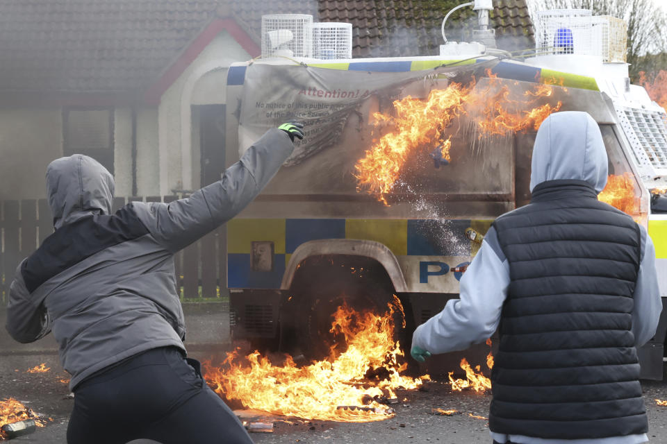 Jóvenes enmascarados lanzan bombas molotov a un vehículo de la policía durante una protesta el lunes 10 de abril de 2023, en Londonderry, Irlanda del Norte. (AP Foto/Peter Morrison)