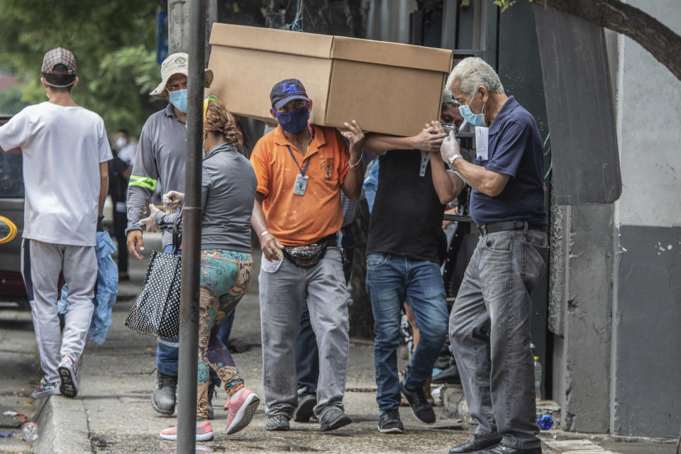 Cemetery workers carry the remains of a person in a cardboard coffin for burial at the General Cemetery in Guayaquil, Ecuador, Monday, April 6, 2020. Guayaquil, a normally bustling city that has become a hot spot in Latin America as the coronavirus pandemic spreads, has untold numbers dying of unrelated diseases that can’t be treated because hospitals are overwhelmed. (AP Photo/Luis Perez)