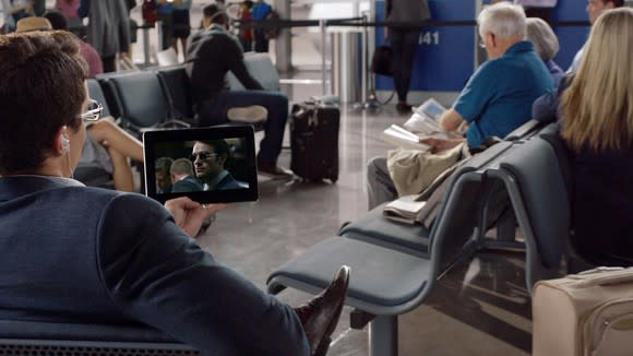 A man watching Netflix on a tablet in the airport.