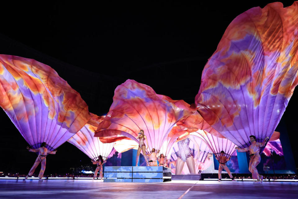 Performers on stage with expansive, wing-like fabric props during a theatrical show