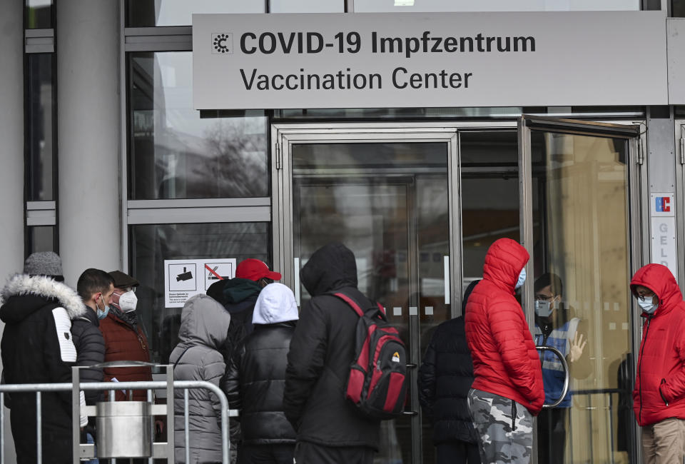 People waiting to be vaccinated queue up at the entrance to the Covid-19 vaccination centre at the Frankfurt exhibition grounds in Frankfurt, Germany, Tuesday, Nov. 30, 2021. Nevertheless, the city of Frankfurt sees its vaccination campaign thwarted by a lack of vaccine. Although the vaccination campaigns of the public health department were very well received by the citizens and the demand had recently increased strongly, the city now had to limit its vaccination offers - because the vaccine quantities ordered by the public health department had been unilaterally reduced by the federal government, the public health department announced on Monday. (Arne Dedert/dpa via AP)