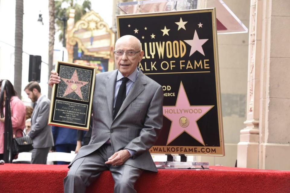 actor and filmmaker alan arkin sits holding his star on the hollywood walk of fame