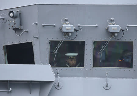 A navy personnel looks out from a window as the Japan Maritime Self-Defense Force destroyer JS Suzutsuki (DD 117) arrives at Qingdao Port for the 70th anniversary celebrations of the founding of the Chinese People's Liberation Army Navy (PLAN), in Qingdao, China April 21, 2019. REUTERS/Jason Lee