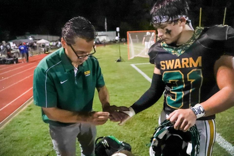 Edgar Bueno prepares to check his son, Sam's blood glucose before the start of the second half against Savannah Christian.
