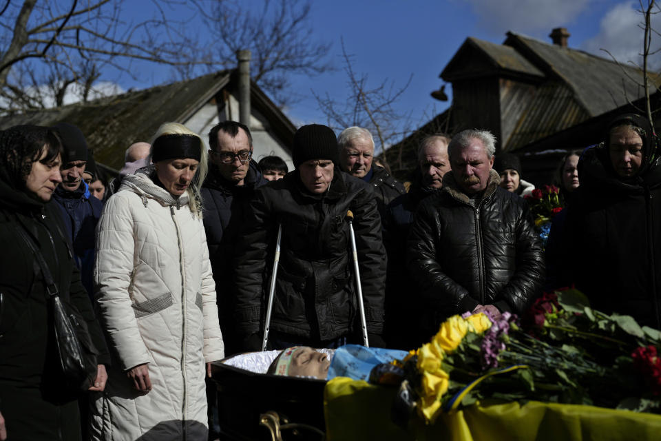 Oleksandr Bondarenko, 42, center, stands next to the body of his brother, Vladyslav Bondarenko 26, during his funeral in Kozyntsi, near Kyiv, Ukraine, Monday, March 6, 2023. Bondarenko, a paratrooper of airmobile brigade, died near Bakhmut on Feb 26. (AP Photo/Thibault Camus)