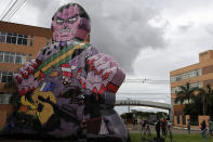 Demonstrators raise large puppet representing Brazil's President Jair Bolsonaro as a killer in front of Brazil's health agency, before agency directors meet to assess the emergency use of China's Sinovac Biotech and the Oxford/AstraZeneca COVID-19 vaccines, at the Anvisa agency's headquarters in Brasilia, Brazil, Sunday, Jan 17, 2021. (AP Photo/Eraldo Peres)