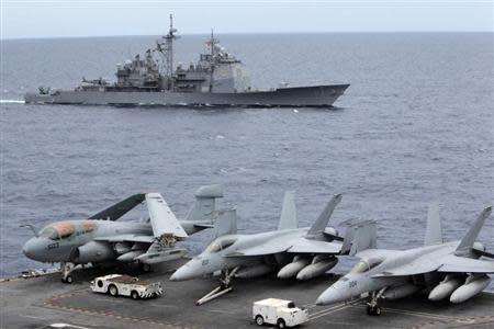 U.S fighter jets on standby at the upper deck of a USS George Washington aircraft carrier while a U.S. Cowpens ship pass during a media tour at the South China Sea, 170 nautical miles from Manila September 3, 2010. REUTERS/Romeo Ranoco