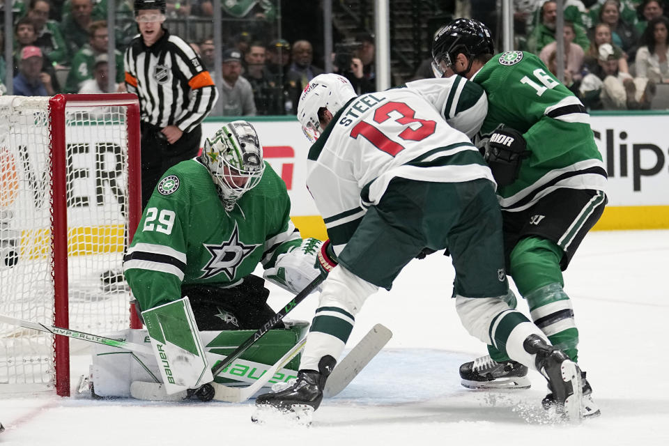 Dallas Stars goaltender Jake Oettinger, left, gets help from Joe Pavelski (16) defending against pressure from Minnesota Wild center Sam Steel (13) in the second period of Game 1 of an NHL hockey Stanley Cup first-round playoff series, Monday, April 17, 2023, in Dallas. (AP Photo/Tony Gutierrez)