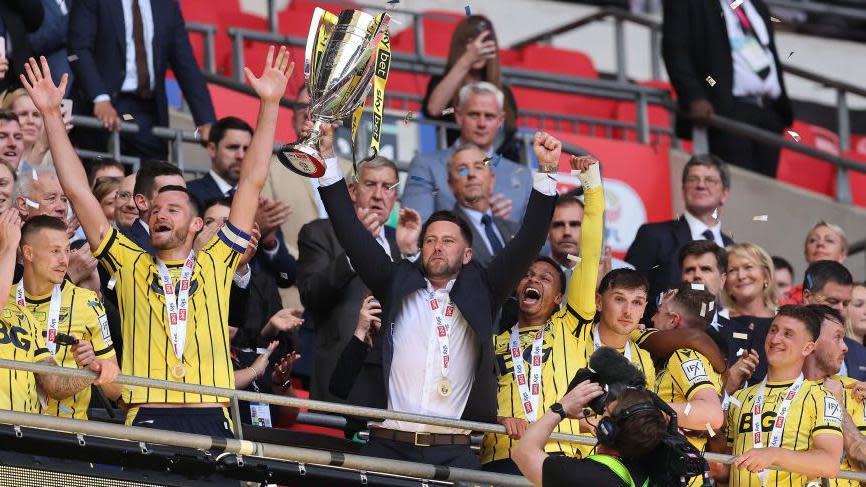Oxford United manager Des Buckingham lifts the League One play-off final trophy