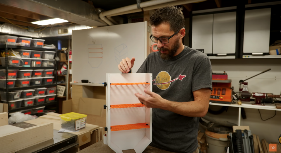 An engineer shows off his DIY white and orange LEGO sorter, which consists of filters inside of a wooden funnel.