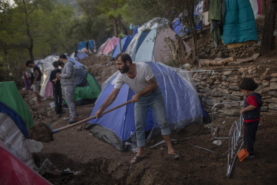 FILE - In this Sept. 25, 2019 file photo, a Syrian man shovels dirt next to his tent near the refugee and migrant camp at the Greek island of Samos island. The head of the U.N. food agency warned of starvation and another wave of mass migration from Syria to Europe unless donors countries step up financial assistance to the war-ravaged country. (AP Photo/ Petros Giannakouris, File)