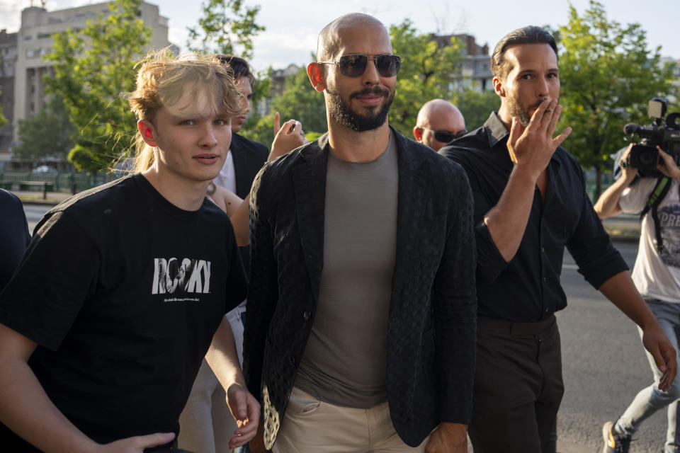 Andrew Tate, left, and his brother Tristan pose with a fan outside the Court of Appeal in Bucharest, Romania, Thursday, July 6, 2023. Andrew Tate, the divisive social media personality and former professional kickboxer who is charged in Romania with rape, human trafficking, and forming a criminal gang to sexually exploit women, lost an appeal on Thursday against a court's earlier decision to keep him under house arrest, his spokesperson said. (AP Photo/Andreea Alexandru)