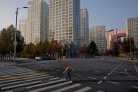 FILE PHOTO: A woman crosses a street during morning rush hour after work-from-home orders kept the Central Business District (CBD) largely empty as outbreaks of the coronavirus disease (COVID-19) continue in Beijing
