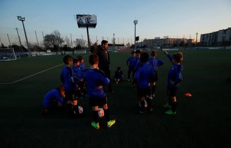 Boys from the RCD Espanyol soccer academy listen to their coach during a training session at Dani Jarque training camp in Sant Adria de Besos, near Barcelona, Spain February 20, 2017. REUTERS/ Albert Gea/Files