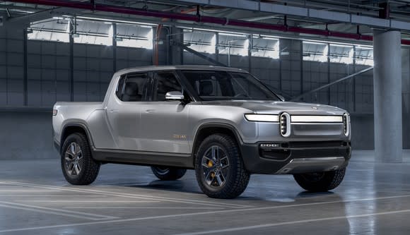 A silver Rivian R1T, a futuristic-looking pickup truck, shown in a garage.