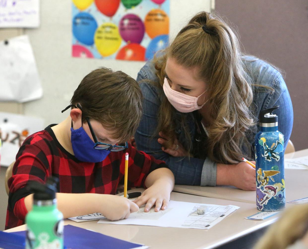 Graham Delauder is helped by teacher Lindsay Fuzer as he creates artwork in his fourth grade class at Strausser Elementary School in Jackson Township. Fuzer's class created drawings that will be etched onto a satellite to be launched by NASA later in 2022. Strausser was one of five schools in the U.S. to be selected for the project.