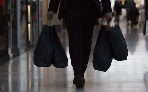 A shopper carries bags from inside the Westfield London shopping centre - Credit: Bloomberg